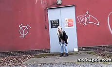 Amateur girl hides behind a wall to take a pee